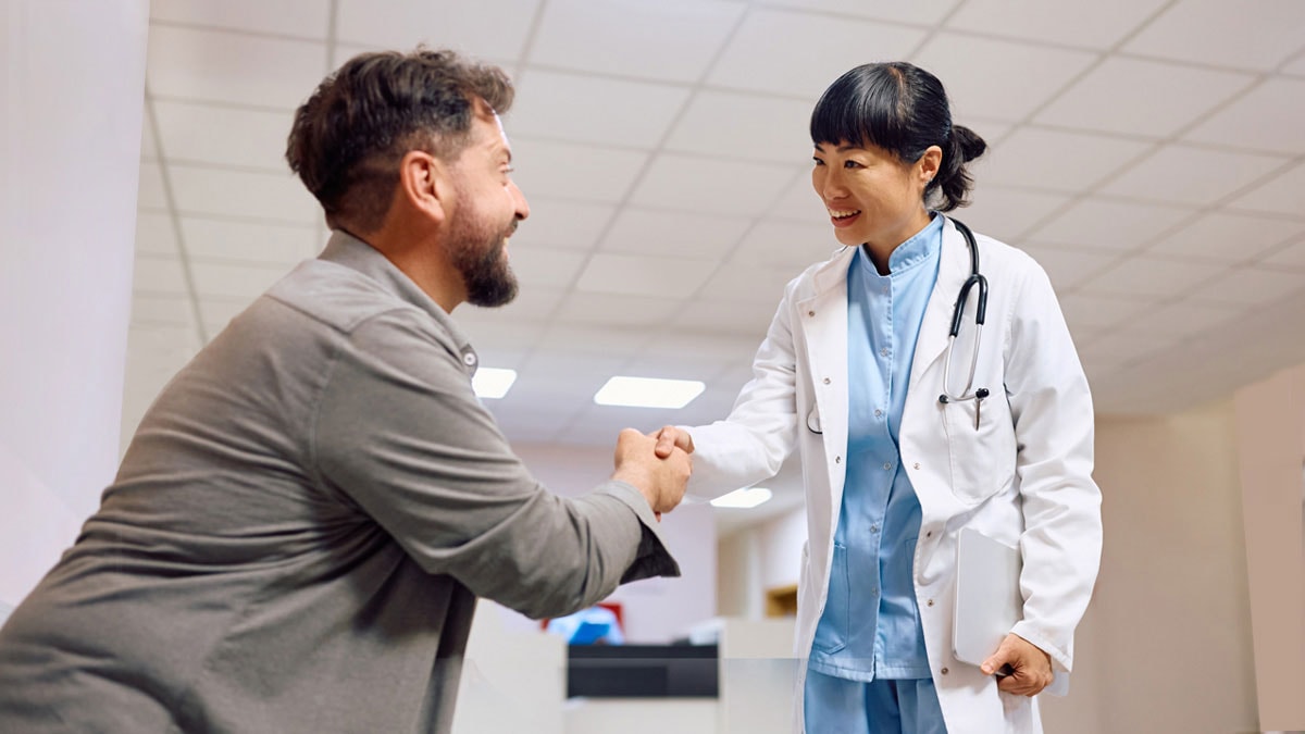 Smiling doctor and her patient greeting in hallway at medical clinic