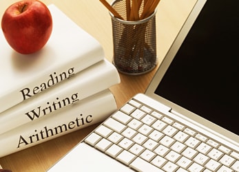 Apple sitting on a stack of books next to a laptop.