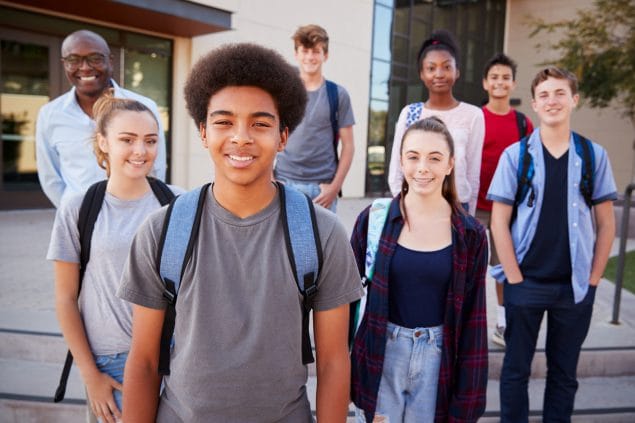 Portrait Of High School Students With Teacher Outside College Buildings