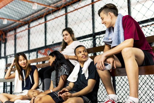 Group of young teenager friends sitting on a bench relaxing