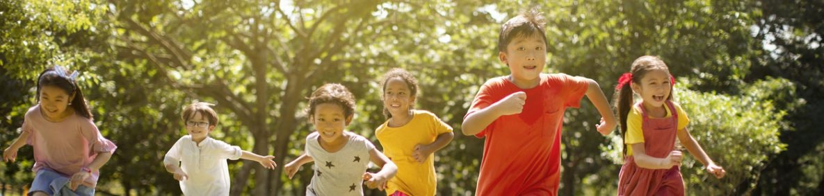 Un grupo de niños riendo y corriendo afuera en la hierba.