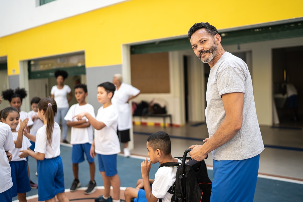 Physical education teacher including a child in a wheelchair in physical activity with other students.