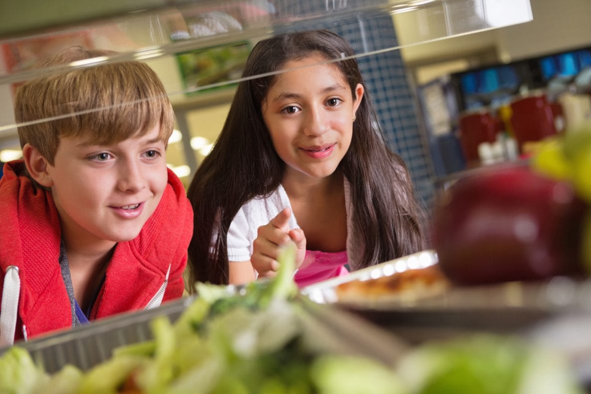 School girl holding food tray in school cafeteria.