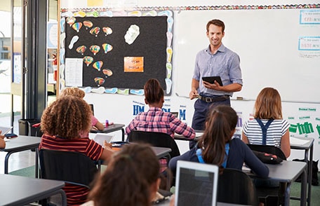 Teacher holding tablet in classroom of students