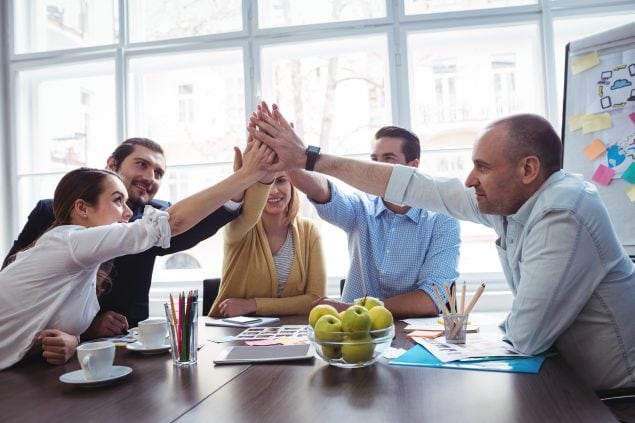 Coworkers giving high fives during meeting