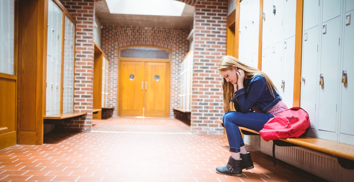 girl sitting in corridor of school looking down