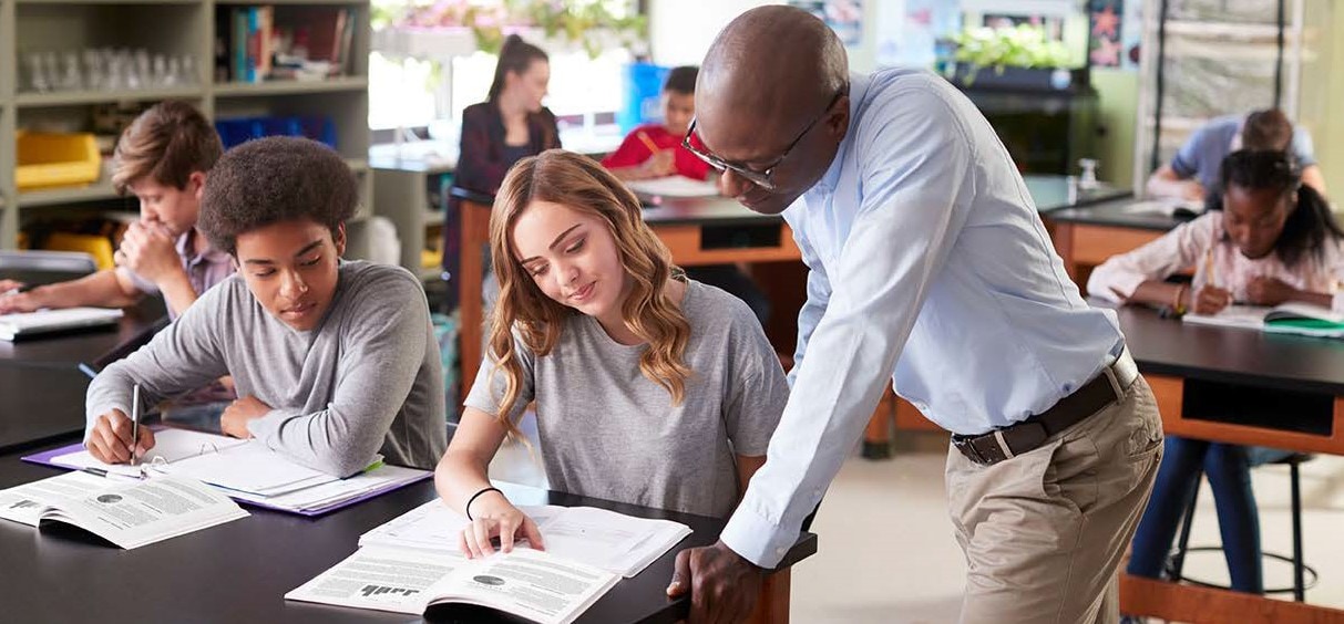 A male teacher helps a female high school student in classroom