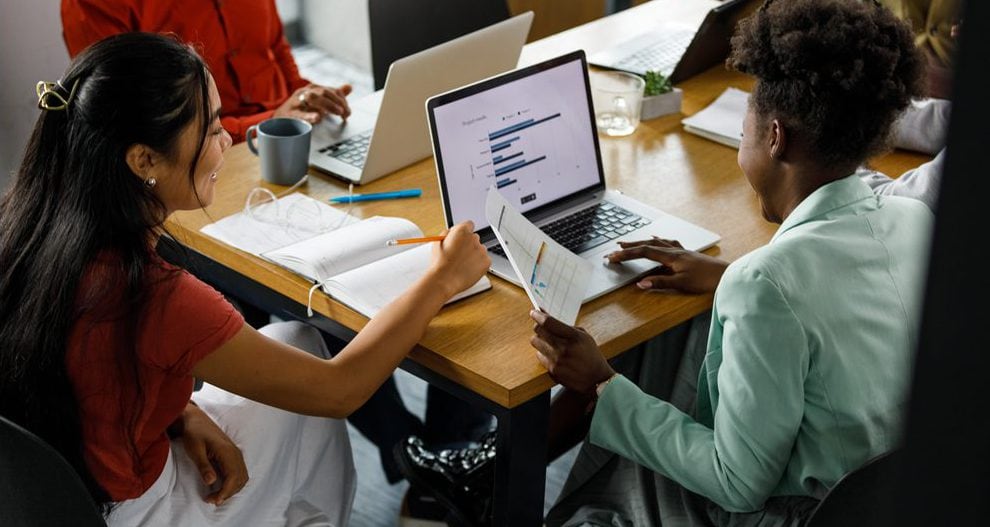 High angle view of two young high school students reviewing a document and data on laptop during a meeting.