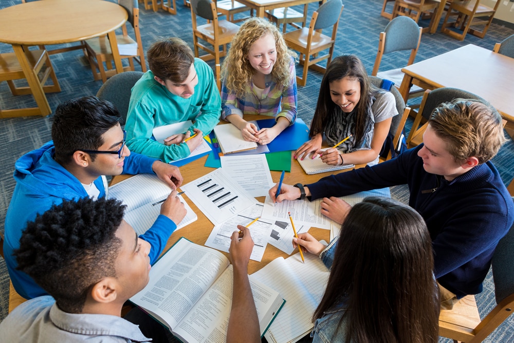 Diverse study group of teenagers studying together in library