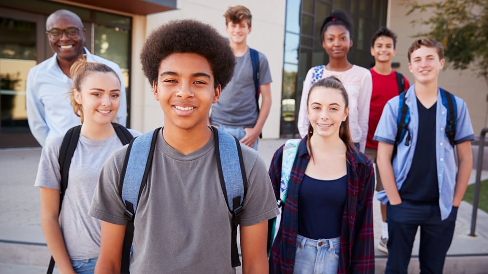 Portrait Of Diverse High School Students With Teacher Outside College Buildings