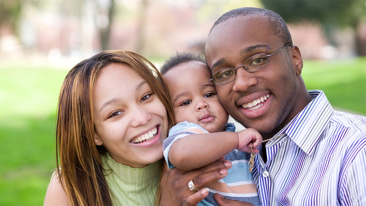 Two parents smiling with their baby