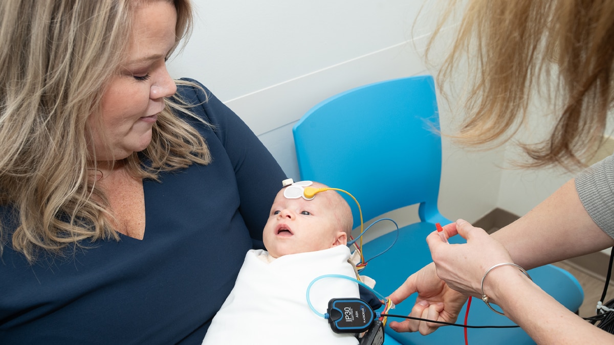 Mother holds infant during hearing screening.