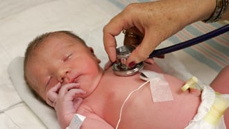 Healthcare provider listening to a baby's heart with a stethoscope.