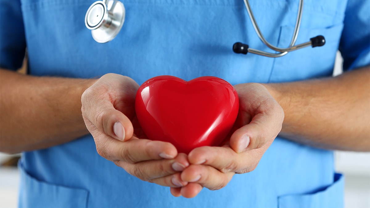 A health care worker holding a red plastic heart in her hands