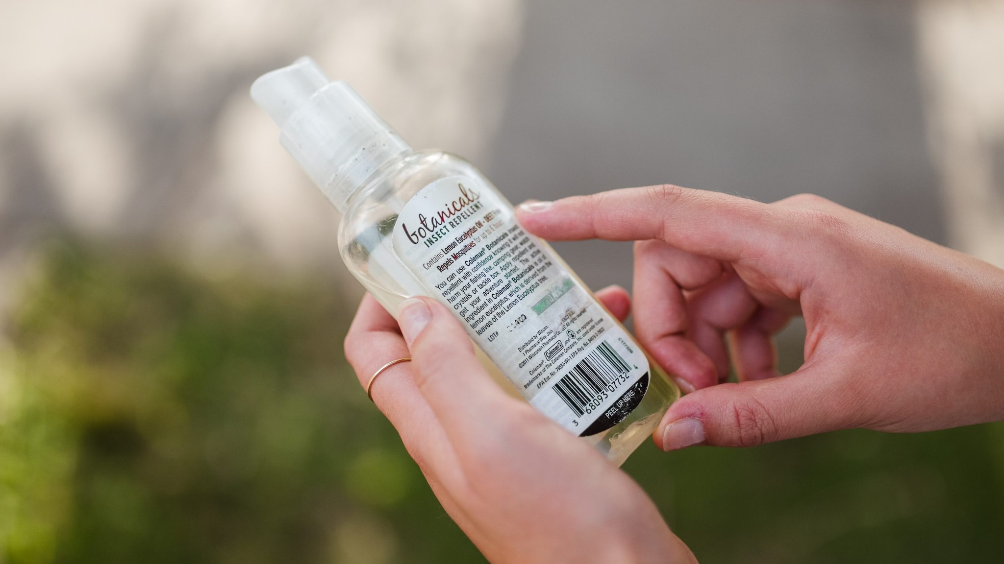 Person reading the back label of a bottle of insect repellent