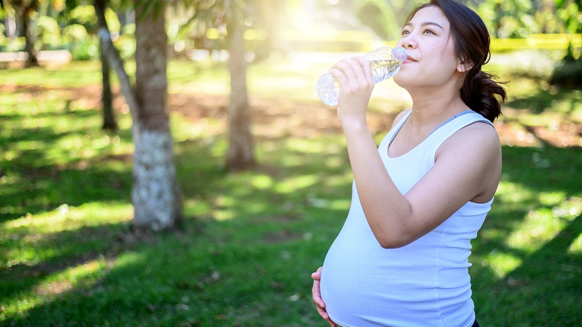 Pregnant woman drinking water in hot weather