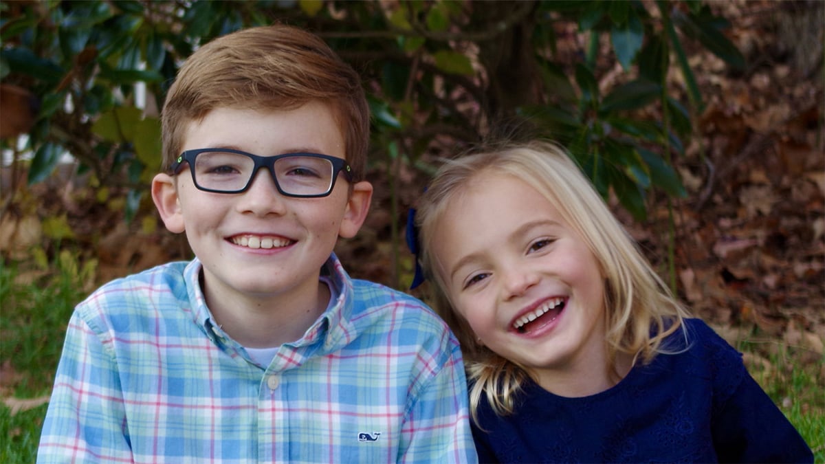 Young boy and girl sitting under a tree and smiling