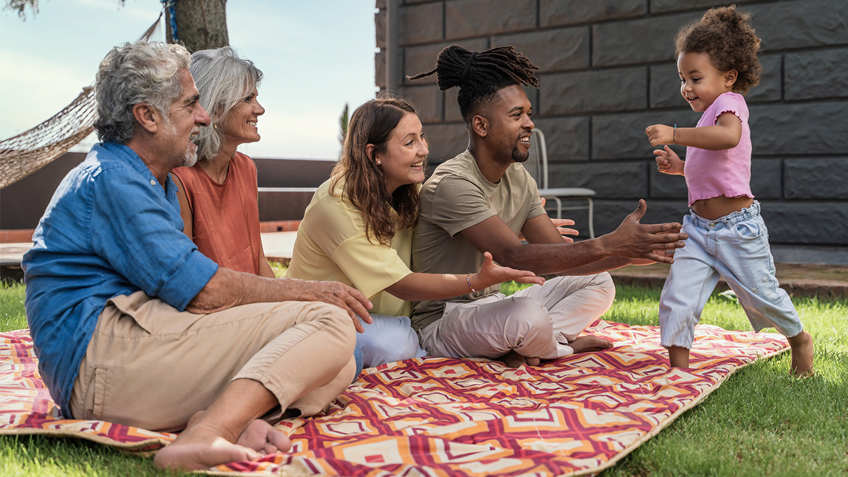 A young multigenerational family plays outside in the grass