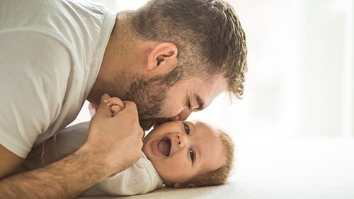 Un padre besando la mejilla de su bebé.