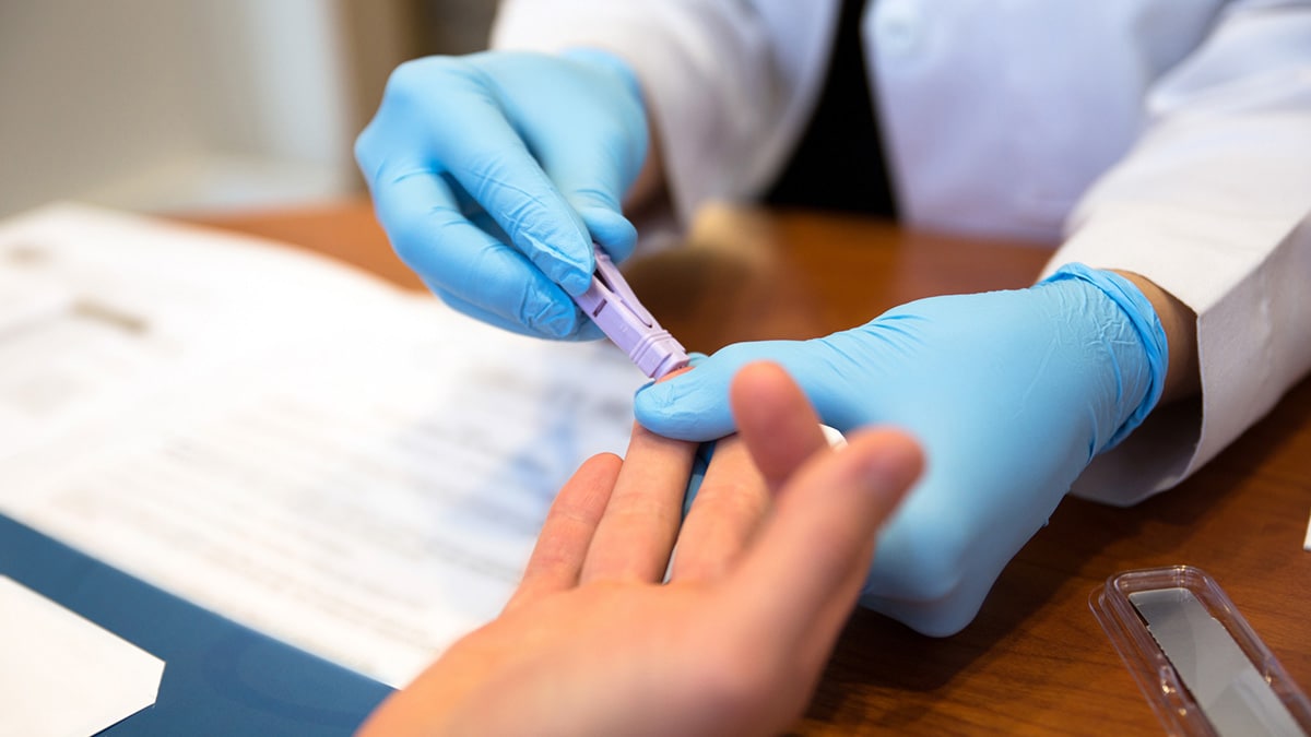 A doctor wearing gloves collects blood from a patient.