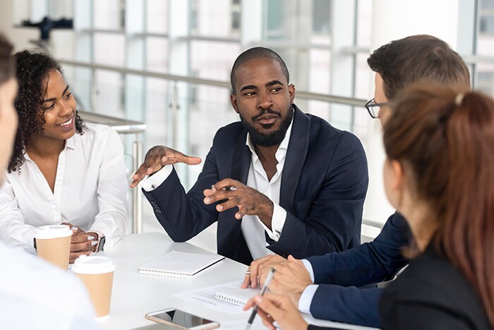 Photo of a team leader addresses team during meeting