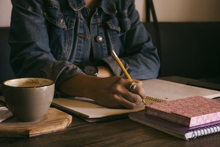 Hand and torso of black woman holding pencil and writing