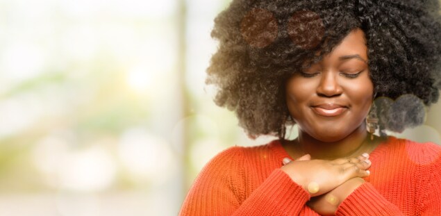 Woman in orange sweater with hands crossed on her chest