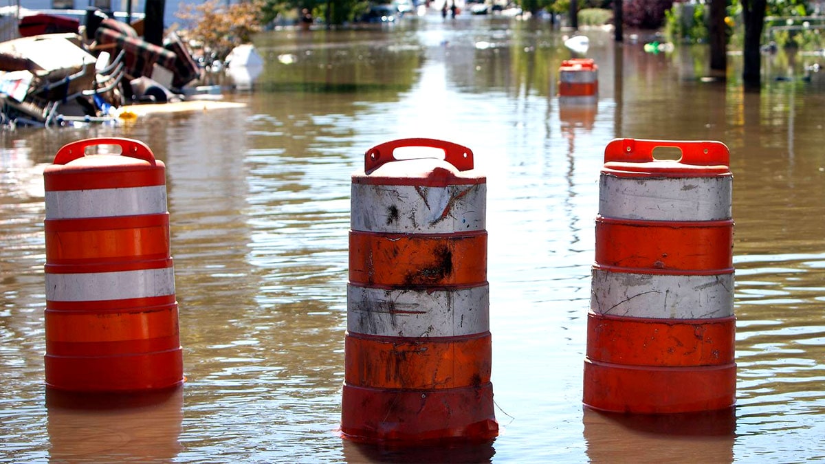 Barriles anaranjados bloqueando una calle inundada