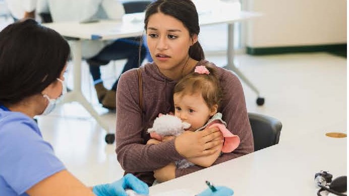 Mom talking to a healthcare provider while holding her baby.