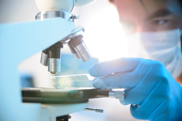 Person examining a specimen under a microscope