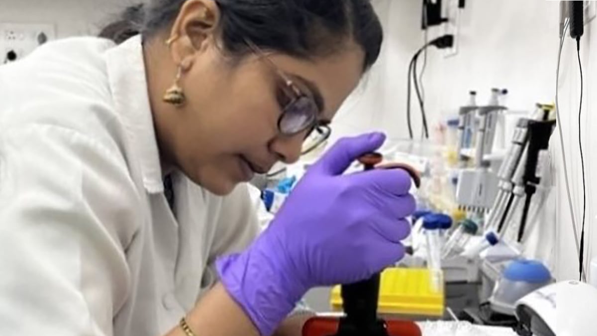 Woman looking into a microscope in a lab in India