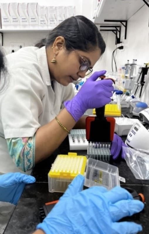 A person in lab coat and gloves uses an instrument for whole genome sequencing in a laboratory.