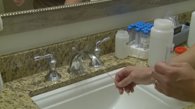 Person swabbing a water faucet.