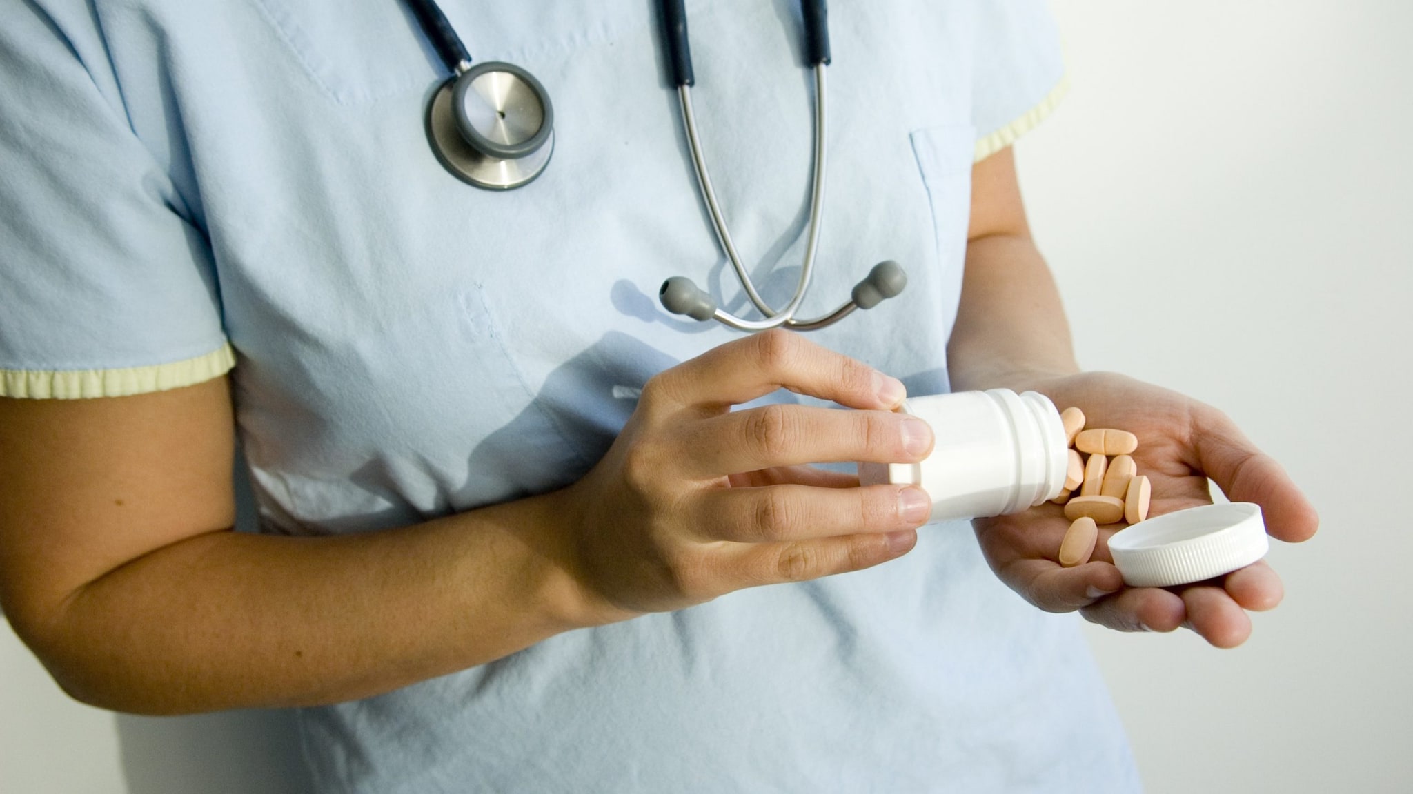 Doctor pouring pills into their hand