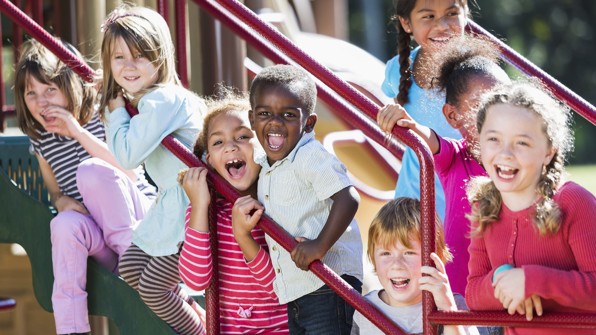 A diverse group of young boys and girls on playground equipment.