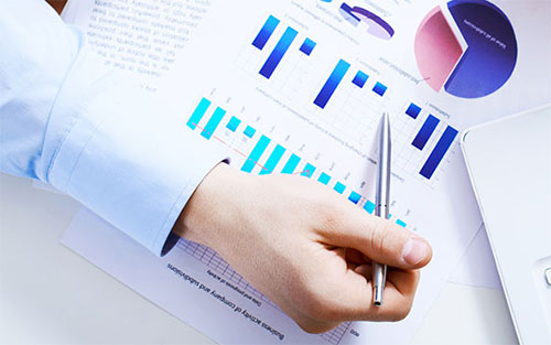 Image of a person's hand and partial arm pointing to bar and pie charts.