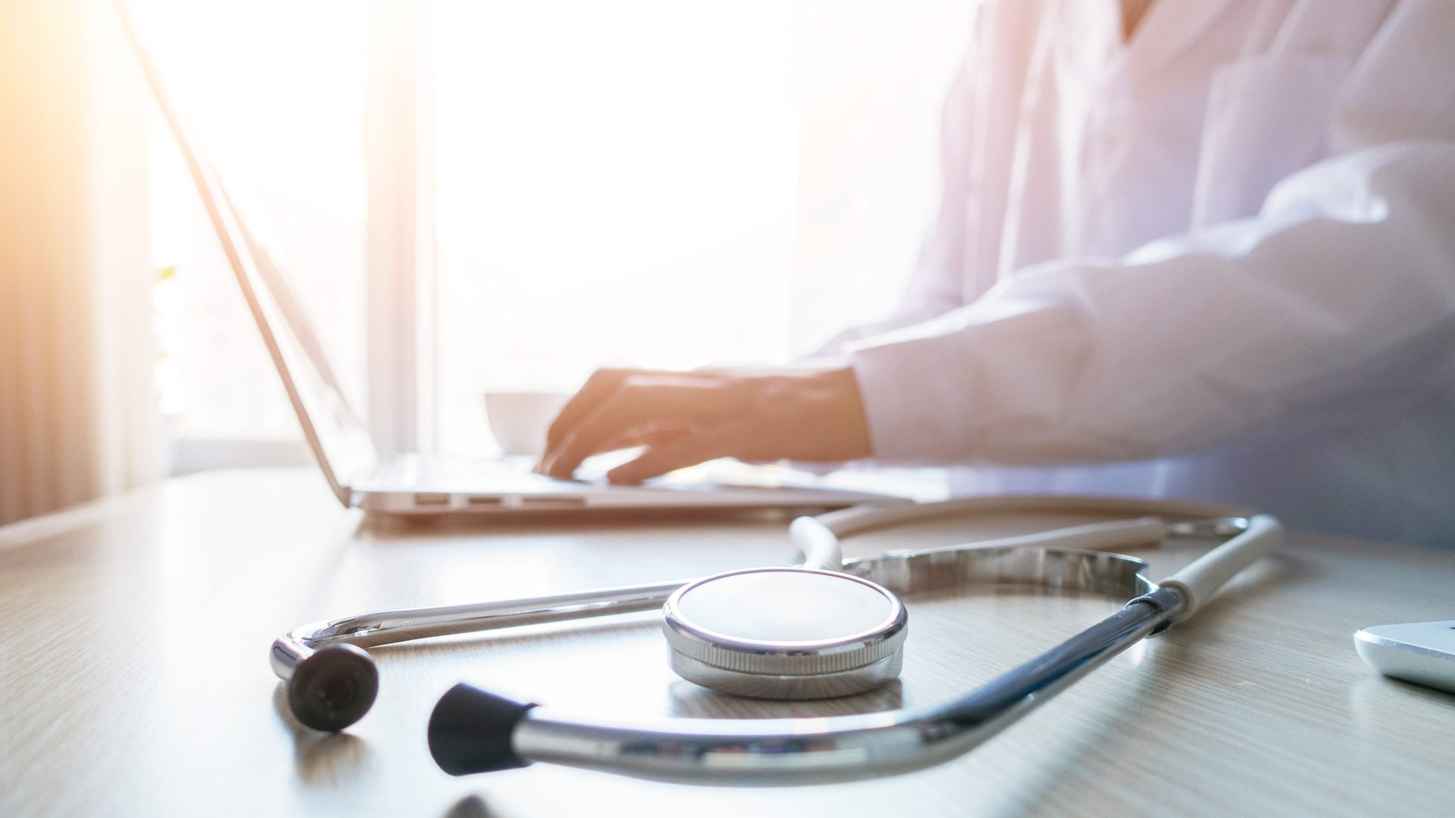 a healthcare provider types on a laptop