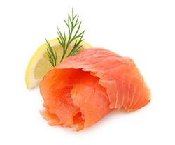 A piece of smoked salmon with a sprig of dill and a slide of lemon.