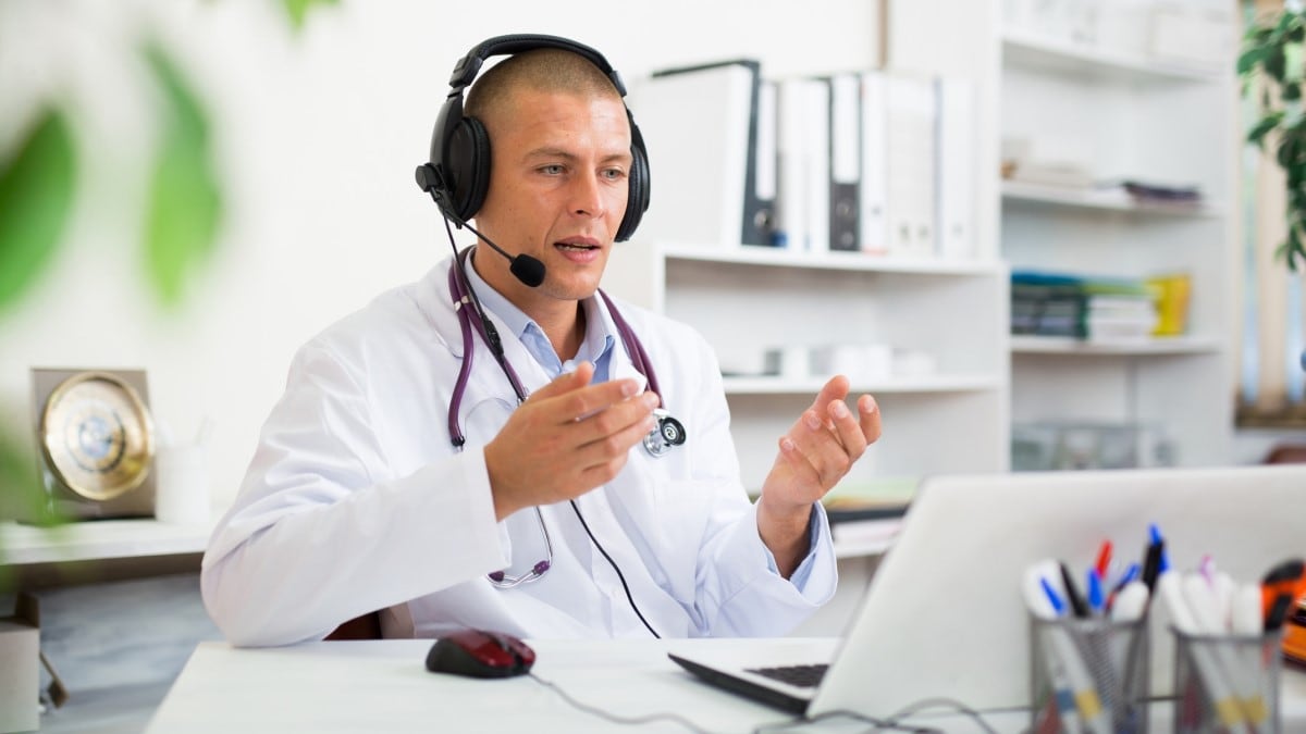 A doctor or pharmacist with his laptop having a phone discussion