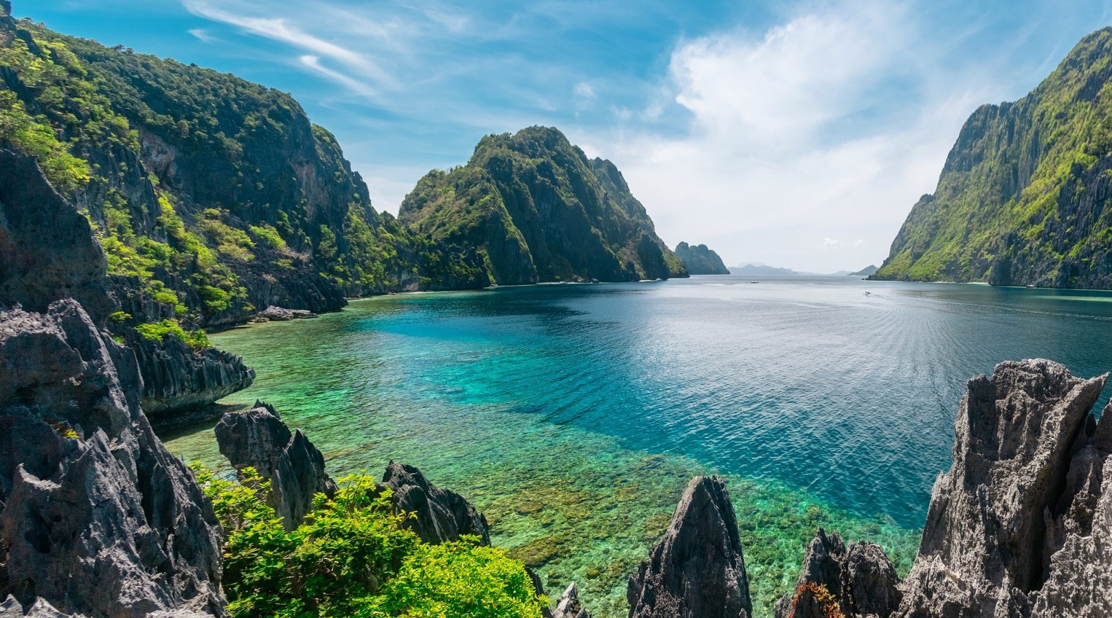 Beautiful, sun-lit view of El Nido, Philippines. Ocean bay surrounded by tall vegetation-covered rock formations