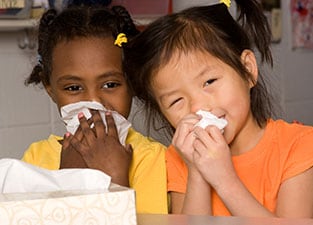 two girls blowing their noses