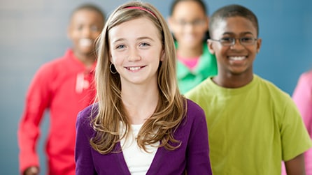 A group of preteens walking down a school hallway.