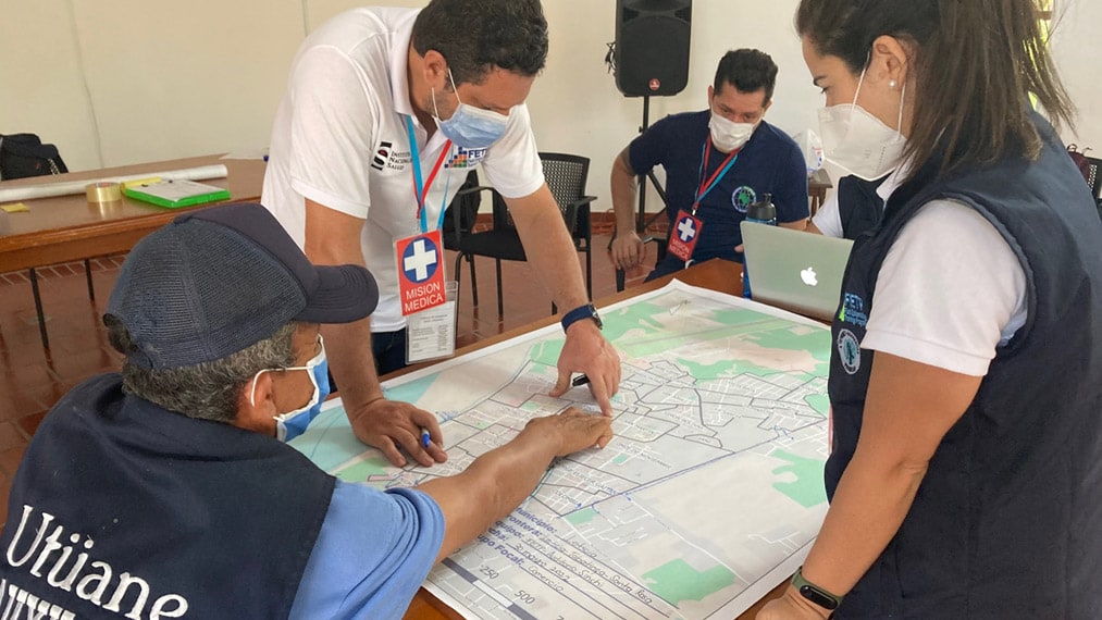 Three health officials looking at border map of Colombia, Brazil and Peru