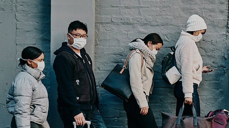 Cuatro personas de pie junto a una pared con su equipaje