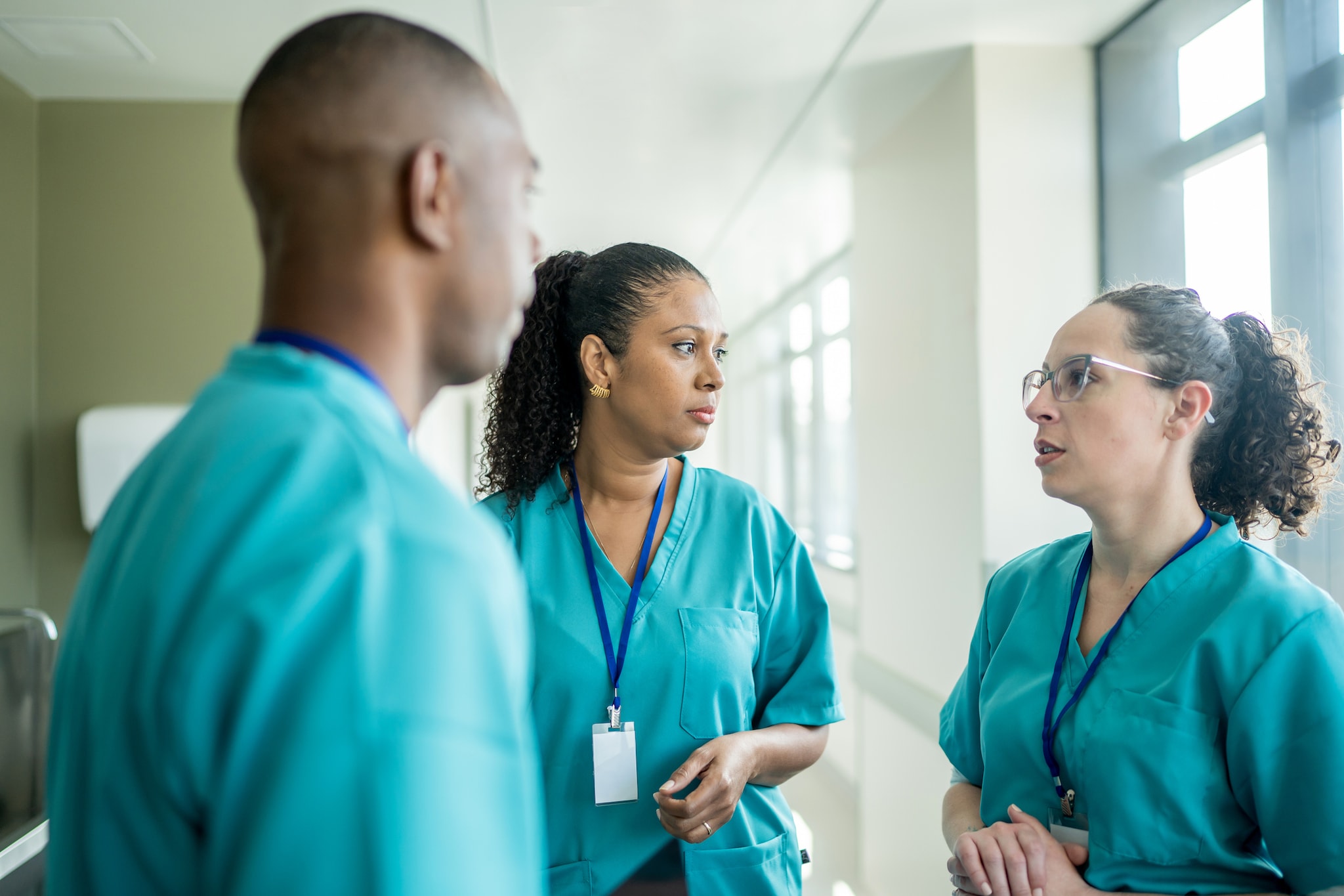 Three health care providers discussing clinical interventions in a hospital setting