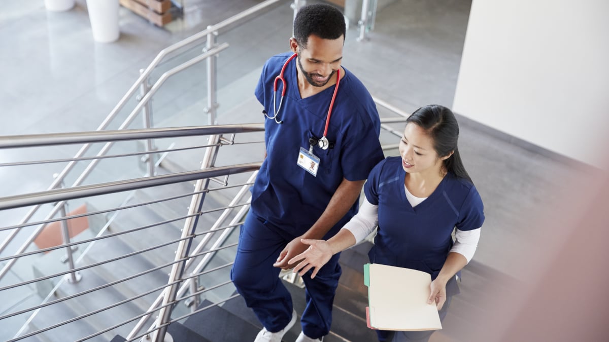 Two clinicians talking while walking up stairs.