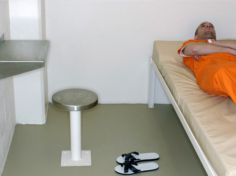 Prison inmate laying on his bed in his cell.