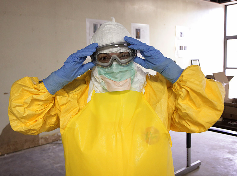 Image of a person fixing their goggles while wearing yellow-colored personal protective equipment (PPE)