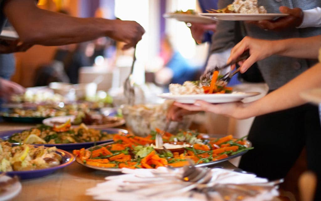 People serving themselves food from buffet table.