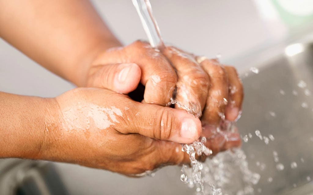 A person washing their hands under running water.